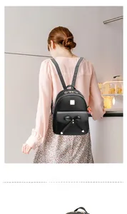Détail du sac à dos en similicuir noir montrant le nœud et les accents dorés