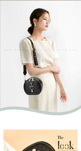 Close-up of quilted black round crossbody bag with metal cat charm and leopard strap