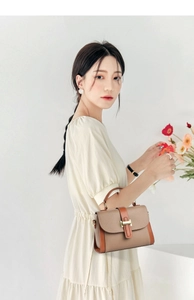 Detail of elegant two-tone crossbody bag with gold H-clasp and leather handle