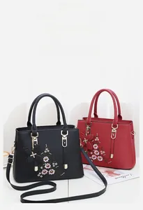 Detailansicht der Blumenstickerei und des Schmetterlingsanhängers an der Tasche