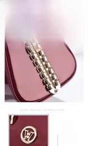 Detailed close-up of wine red patent leather bag with gold rivets and fashion logo