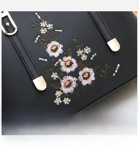 Details der Blumenstickerei und goldener Metallbeschläge auf schwarzer Handtasche