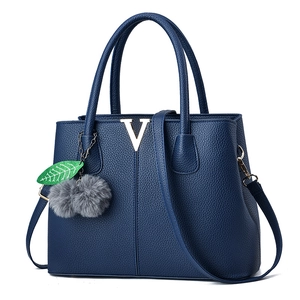 Dunkelblaue Handtasche mit Litschistruktur, goldenem V-Logo und dekorativem Fellanhänger
