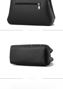 Detail view of the black textured leather handbag showing the back pocket and wide bottom