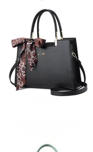 Detail der schwarzen Handtasche aus Leder mit Lychee-Struktur und dekorativem Seidentuch