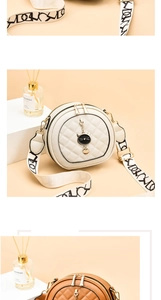 Detail of quilted round crossbody bag with cat charm and wide woven strap design