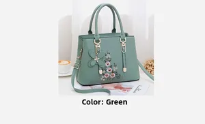Details der grünen Handtasche mit Blumenstickerei, Goldbeschlägen und Schleife