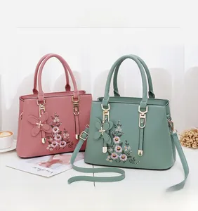 Nahaufnahme von Handtaschen in Rosa und Mintgrün mit Blumenstickerei und Schmetterling-Anhänger