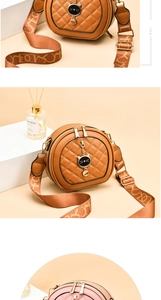 Detail of round quilted shoulder bag with cat-head pendant and wide woven strap