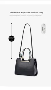 Detail of black crocodile texture handbag with floral silk scarf on handle and metal hardware