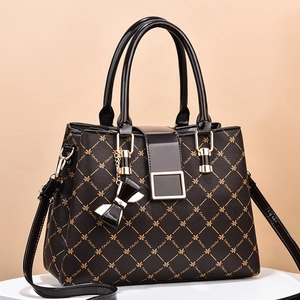 Fashionable floral print satchel bag with gold hardware and butterfly charm on display