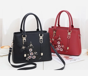 Details von Blumenstickereien und 3D-Schmetterlingsanhängern an PU-Ledertaschen in Schwarz und Rot