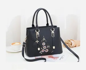 Detailansicht der schwarzen Handtasche mit Blumenstickerei und elegantem Schmetterlingsanhänger