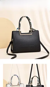 Detail of crocodile texture handbag with gold handles and decorative silk scarf