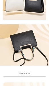 Detail of crocodile pattern handbag with metal handles and decorative silk scarf accessory