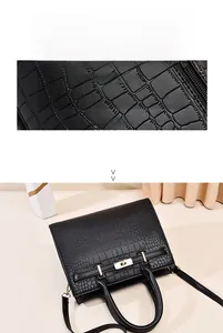 Vue détaillée de la texture cuir crocodile noir et du fermoir rotatif doré du sac