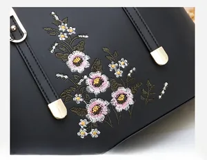 Nahaufnahme aufwendiger Blumenstickerei und goldener Metalldetails an schwarzer Tasche
