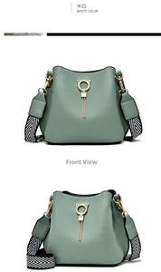 Detail of mint green bucket bag featuring a gold cat ring charm and woven shoulder strap