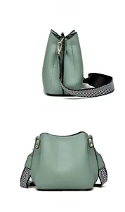 Detail view of bean green leather bucket bag with a zigzag wide woven shoulder strap
