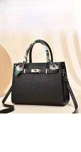 Close-up of black crocodile embossed tote bag with gold lock and silk scarf detail