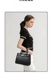 Détail du sac à main noir à motif crocodile avec doubles poignées et fermoir tournant en métal