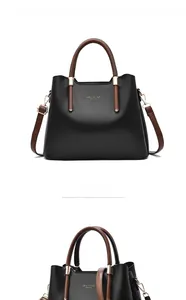 Detail view of large capacity black tote bag with brown handles and golden metal hardware