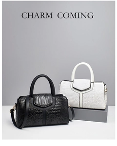 Detail of black and white crocodile textured handbags with gold hardware and top handles