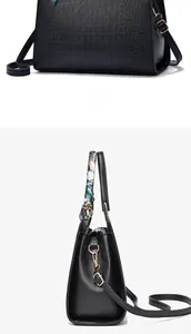 Detail of black crocodile texture handbag with silk scarf handle and gold hardware