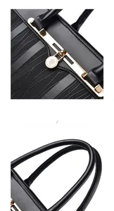 Detail of black leather handbag featuring golden floral lock and rounded handle