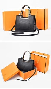 Detail of black crocodile texture handbag with silk scarf handle and orange gift box