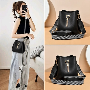 Elegant black bucket bag with gold cat-ear hardware and patterned wide strap