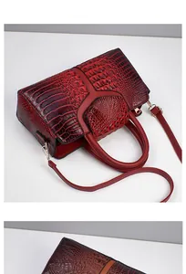 Detail shot of the deep red crocodile-embossed texture and Y-shaped leather stitching