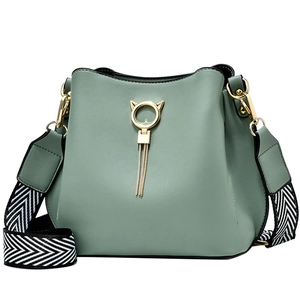 Light green bucket bag with golden cat ear ring, tassel detail and wide fabric strap