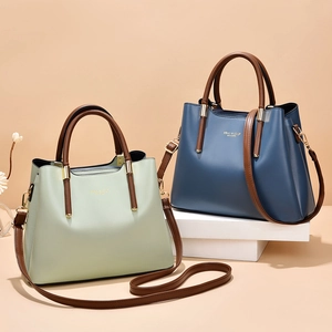 Green and navy blue leather tote bags with top handles and detachable gold hardware straps