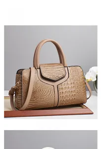 Detail of khaki faux crocodile leather handbag with golden hardware on wooden tray