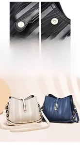 Detail of wave-textured bucket bags with gold hardware and chain straps in navy and beige