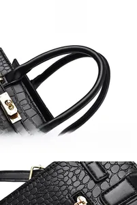 Gros plan sur la texture crocodile noire et le fermoir doré tournant du sac à main