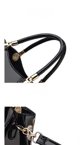 Close-up of black patent leather handle and gold metal hardware of the Boston bag