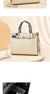 Detail view of beige crocodile embossed handbag with silk scarf handle and gold hardware