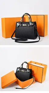 Detail of black crocodile texture handbag with gold buckle and orange gift packaging