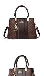 Detail der dunkelbraunen Handtasche mit goldenem Logo, Monogramm und Blattanhänger