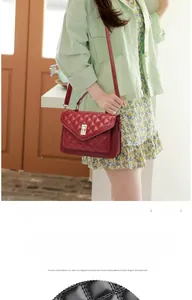 Detail of red quilted crossbody bag featuring a golden metallic twist-lock closure