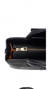Detail of gold zipper closure and crocodile texture on black shoulder bag with brown lining