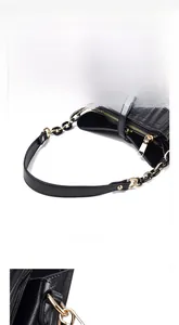 Detail view of black textured leather bucket bag with gold zipper and chain handle