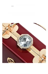 Close-up of shiny dark red patent leather evening bag with octagonal diamond gold clasp