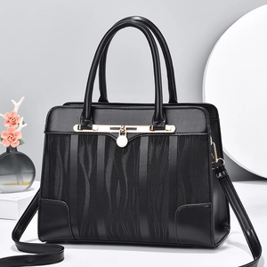 Structured black handbag with wave embossing and gold clasp on a minimalist background