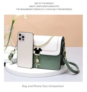 Detail of crossbody bag with quilted heart pattern and Mickey mouse charm near iPhone