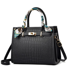 Fashionable black crocodile embossed handbag with gold hardware and a silk scarf handle