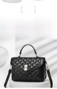 Close-up of black quilted handbag with golden twist lock on white geometric platform