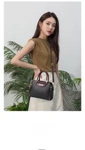 Detail of color-block black and wine red handbag with gold hardware and shoulder strap